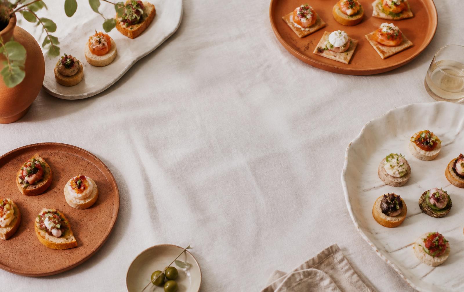 Assorted fingerfood canapés arranged on platters over cream linen